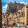 A street lined with traditional stone buildings with Edinburgh Castle atop Castle Rock in the distance